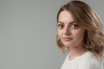 Portrait of a young attractive woman with blond hair on a neutral gray background.