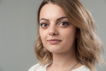 Obraz premium Portrait of a young attractive woman with blond hair on a neutral gray background.