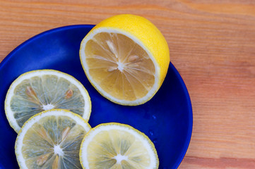 Composition with lemons on a wooden background. Lemons on a blue plate.Fresh yellow lemons, sliced...