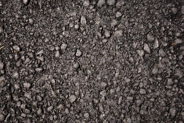 Close up of black asphalt with colored stones. Rough surface. Abstract texture background