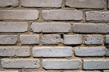 Fragment of weathered wall of old building made of grey bricks. Abstract texture background