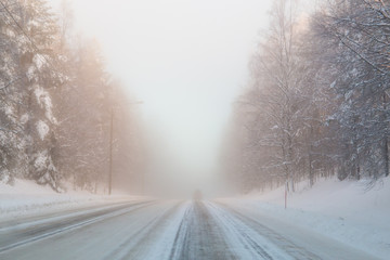 Fototapeta na wymiar Winter snow-covered road in Finland. Heavy fog.