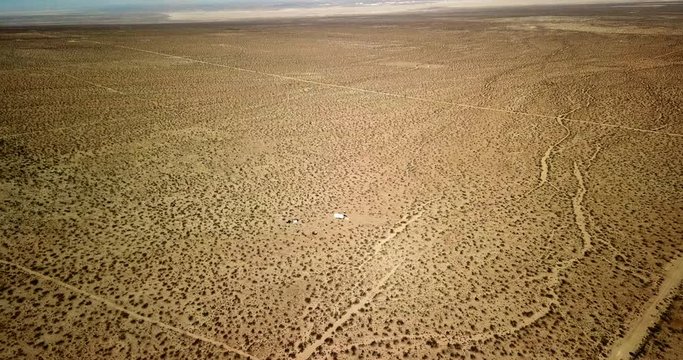 Aerial View: Vast, Flat, Desert Landscape with Dirt Tracks & a Trailer in Joshua Tree, California