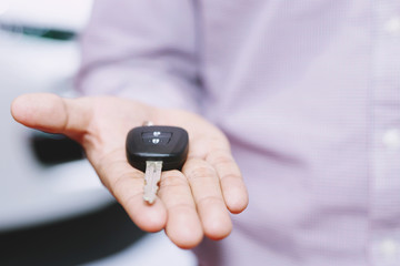 Car key, businessman handing over gives the car key to the other man on car background.	