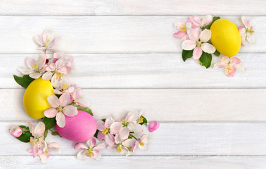 Easter decoration. Pink flowers apple tree and colored easter eggs on background of white painted wooden planks with space for text. Top view, flat lay