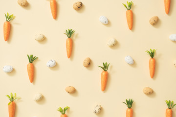 Easter eggs and carrots on pastel yellow background. Easter holiday concept. Minimal composition.