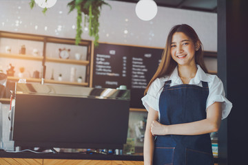 Pretty young asian waitress standing arms crossed in cafeteria.Coffee Business owner Concept. ...