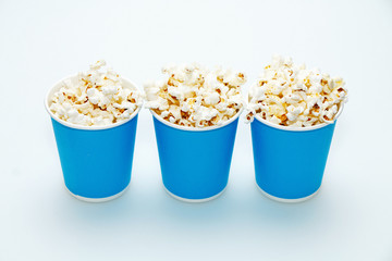 Three blue glasses with popcorn on a white background