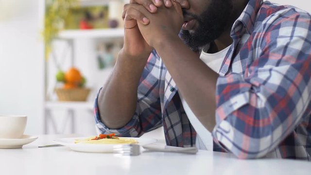 African american man praying before eating, asking god to bless food, faith