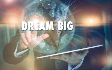A hand selecting a Dream Big business concept on a futuristic computer display.