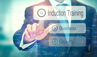 A business man selecting a button on a futuristic display with a Induction Training concept written...
