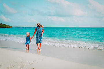 mother with kids walk on beach, family vacation