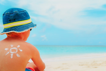 sun protection- little boy with suncream at tropical beach