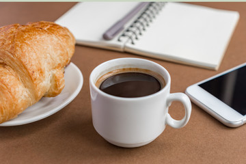 Coffe break with croissant and espress. Freelancer at work.