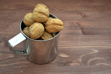 Antioxidant and organic concept, walnut in metalic mug on wooden background with copy space