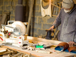 Carpenter works in the workshop of processing wooden boards, grinding machine, sander in the hands of a worker