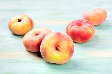 A photo of vibrant organic flat saturn peaches on a teal background with a place for text