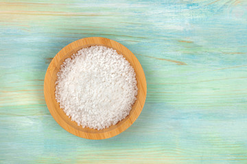 A bowl of salt, shot from the top on a teal blue background with a place for text