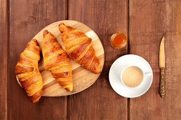 French breakfast. Croissants, shot from the top on a dark rustic wooden background with coffee, jam, and copyspace