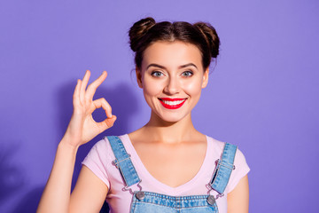 Close up photo beautiful amazing she her lady buns show white teeth toothy hold arm hand okey symbol perfection wear casual t-shirt jeans denim overalls clothes isolated purple violet background