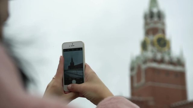 Tourist girl takes mobile phone photos of historical landmark on red square. Russia trip. Photographer woman take pictures of the Red Square in Moscow with smartphone or mobile device