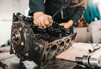 Auto mechanic adjusting cylinder head on engine block at workshop.