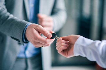 Businessman giving key to a customer, close-up.