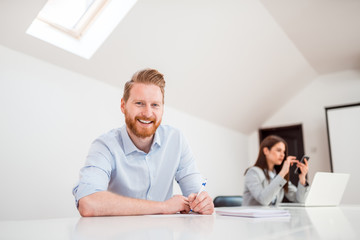 Portrait of a ginger businessman in bright co working space.