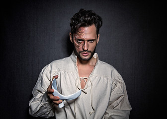 Young attractive man with face scars and a white mask, dressed in a Phantom of the Opera look
