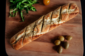 Delicious baguette sandwich on a wooden board, top view.