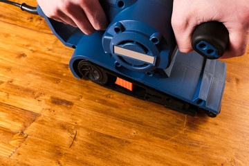 Fototapeta premium sandar tool with mans hands on wooden background