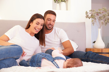 Happy young family relaxing in bad and playing together with their baby girl