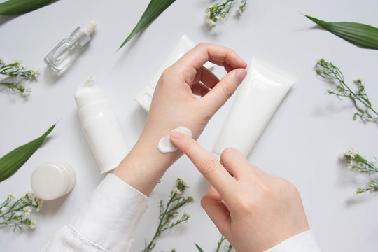 Scientist/Pharmacist applying moisturizer lotion on her hand for efficacy testing of natural organic skincare products in laboratory. Beauty cosmetic research and development concept. Top view.