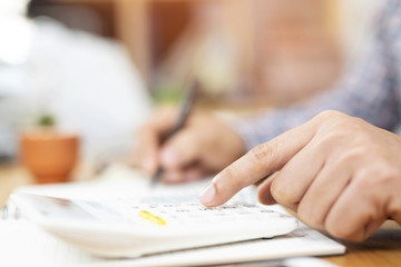 Close up business man hand is writing in a notebook and using calculator counting making notes Accounting at doing finance on desk at office. Savings finances concept. note pad