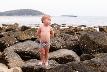 Little boy standing on the sea rocks