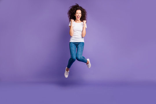 Full length body size photo yelling beautiful she her lady fists cheerleader jump high discount sale shopping wear casual jeans denim white t-shirt sneakers isolated purple violet bright background