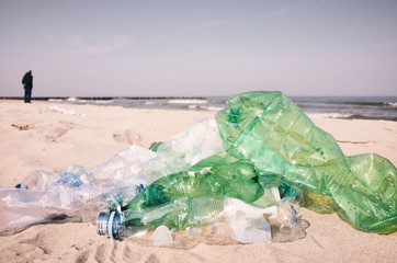 Used plastic bottles left on a beach by tourists, selective focus, color toning applied.