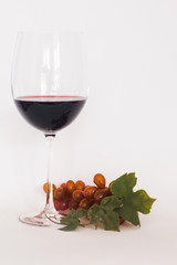 Glass of red wine with a bunch of grapes