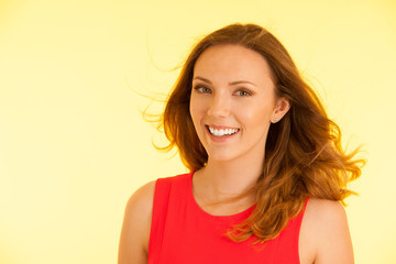 Beautiful young haapy woman in vibrant dre dress over yellow background