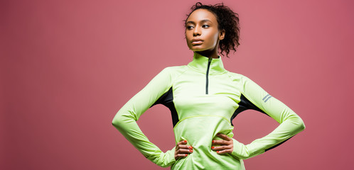 panoramic shot of beautiful african american sportswoman in track jacket isolated on pink with copy space