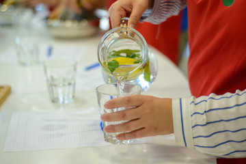 drink with lemon and mint pour from a decanter into a glass in the kitchen