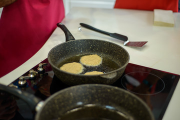 in the kitchen on a black frying pan are grilled small pancakes or cutlets