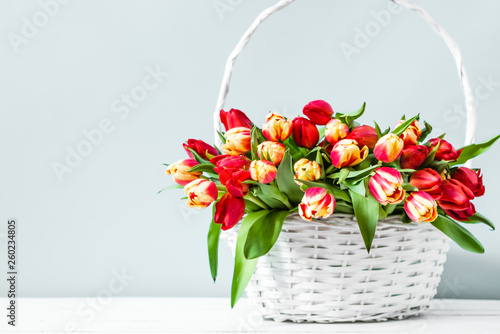 Basket with flowers on bright background. Mother's day tulip gift.