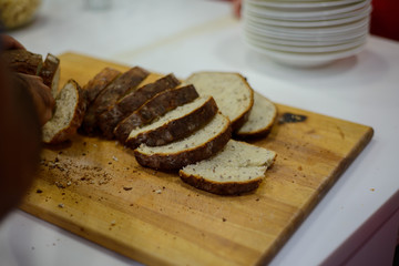 round black bread with a ruddy crust on a wooden board in the kitchen is sliced in small slices