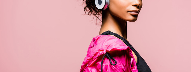 panoramic shot of african american sportswoman in windbreaker and headphones isolated on pink with copy space © LIGHTFIELD STUDIOS