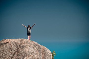 Girl standing on the mountain top over blue sea view