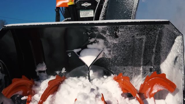 Cleaning the territory with the help of a snowblower during a snowfall.