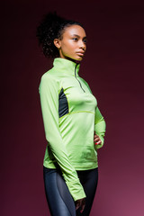 beautiful african american sportswoman in track suit posing on dark