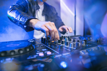 Dj mixing at party festival with blue lights and smoke in background - Summer nightlife view of disco club inside. Focus on hand