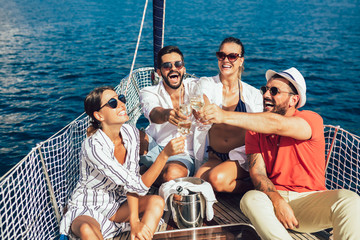 Smiling friends with glasses of champagne on yacht. Vacation, travel, sea, friendship and people concept